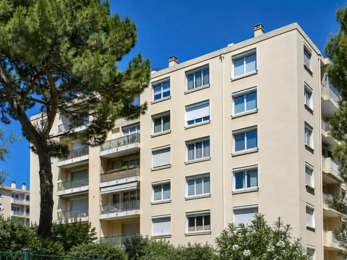 Façade de résidence marseillaise des années 1970 aux fenêtres PVC blanches sous un ciel bleu, intervention à Salon-de-Provence
